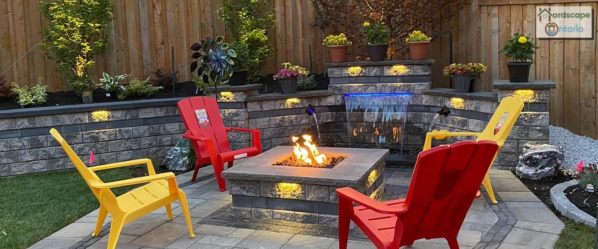 Amazingly designed patio with a gas fire pit, retaining walls and water fountain with trees and flowers